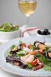 Photo of Plate of delicious salad with seafood on white tiled table, closeup