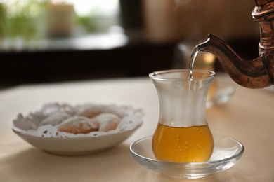 Pouring hot tea into glass cup on table