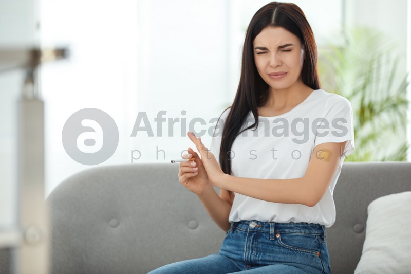 Photo of Emotional young woman with nicotine patch and cigarette at home. Space for text