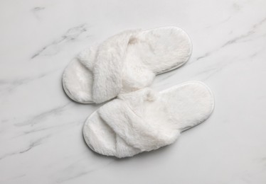 Pair of soft slippers on white marble floor, top view