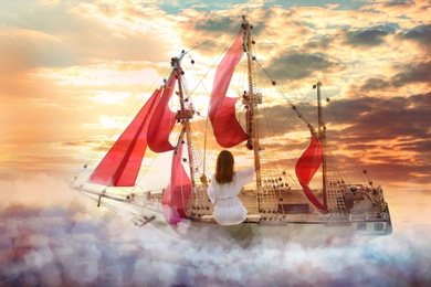 Dream world. Sailing ship with beautiful girl on board floating among wonderful fluffy clouds