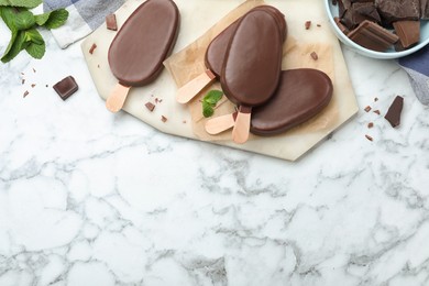 Delicious glazed ice cream bars with mint and chocolate on white marble table, flat lay. Space for text