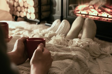 Couple in knitted socks near fireplace at home, closeup