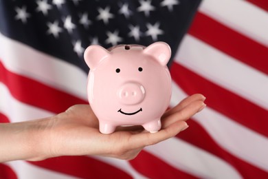 Photo of Woman holding piggy bank against American flag, closeup