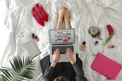 Woman and laptop with beauty blogger site on bed, top view