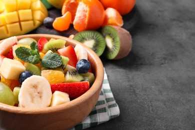 Delicious fresh fruit salad on grey table, space for text