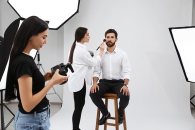 Photo of Professional photographer and stylist working with model in modern photo studio