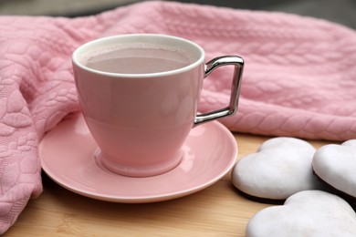 Photo of Cup of tasty cocoa, pink sweater and cookies on wooden table