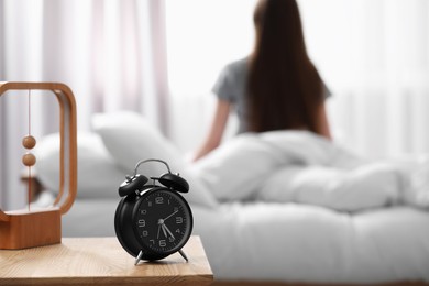 Photo of Woman on bed at home in morning, focus on alarm clock. Space for text