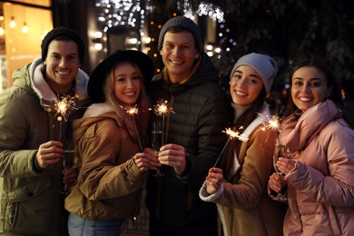 Group of happy friends with sparklers and champagne at winter fair