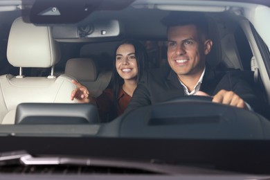 Photo of Young woman and taxi driver in modern car, view through windshield