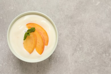 Delicious yogurt with fresh peach and mint on grey table, top view. Space for text