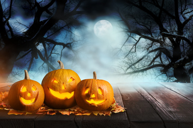 Image of Scary Jack O Lantern pumpkins surrounded by mystical mist under full moon on Halloween. Space for text