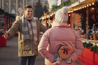 Young woman presenting Christmas gift to her boyfriend at winter fair