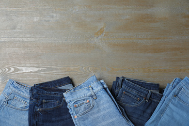 New stylish jeans on wooden background, flat lay. Space for text