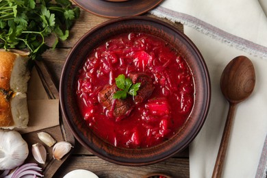 Stylish brown clay bowl with Ukrainian borsch served on wooden table, flat lay