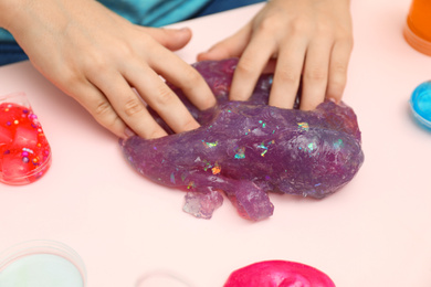 Child playing with purple slime at table, closeup