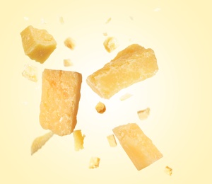 Pieces of delicious parmesan cheese flying on beige background