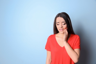 Woman with sensitive teeth on color background