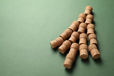 Photo of Christmas tree made of wine corks on green background. Space for text