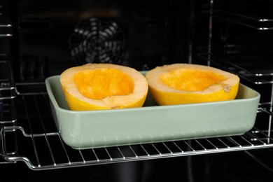 Baking dish with halves of fresh spaghetti squash in oven
