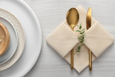 Elegant cutlery with green leaves on table, flat lay. Festive setting