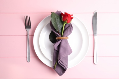 Beautiful table setting for romantic dinner on pink wooden background, flat lay. Valentine's day celebration