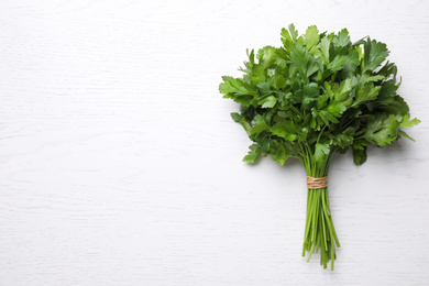 Bunch of fresh green parsley on white wooden table, top view. Space for text