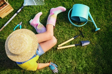 Young woman and gardening tools on green grass, above view