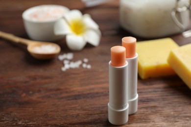 Hygienic lipsticks with natural beeswax component on wooden table. Space for text
