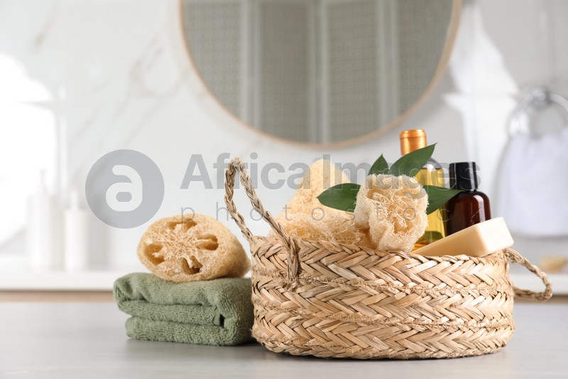Photo of Natural loofah sponges, personal hygiene products and towel on table indoors