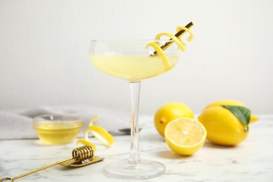 Delicious bee's knees cocktail and ingredients on white marble table