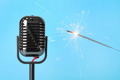 Making ASMR sounds with microphone and burning sparkler on light blue background, closeup