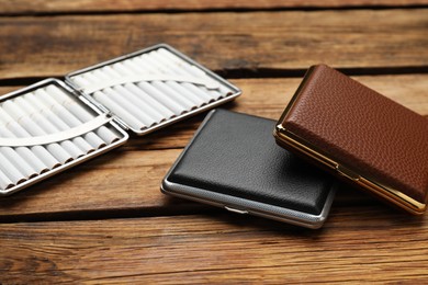 Stylish leather cigarette cases on wooden table