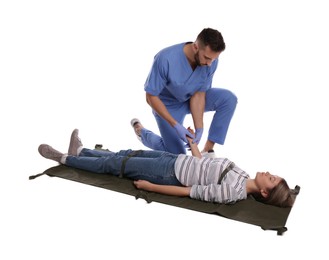 Doctor in uniform fixing woman on stretcher 
against white background. First aid