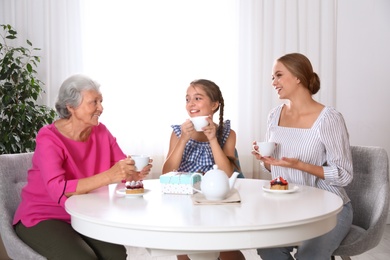 Beautiful mature woman, her daughter and grandchild having tea at home. Happy Mother's Day