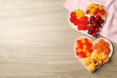 Delicious gummy candies and fresh fruits on wooden table, flat lay. Space for text