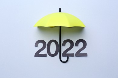 Mini umbrella and number 2022 on white background, top view