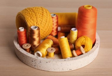 Color sewing threads in tray on wooden table