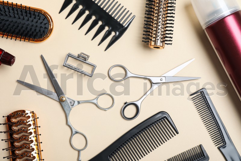 Flat lay composition of professional scissors and other hairdresser's equipment on beige background. Haircut tool