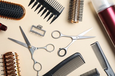 Photo of Flat lay composition of professional scissors and other hairdresser's equipment on beige background. Haircut tool