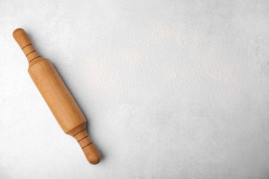 Rolling pin and flour on light grey table, top view