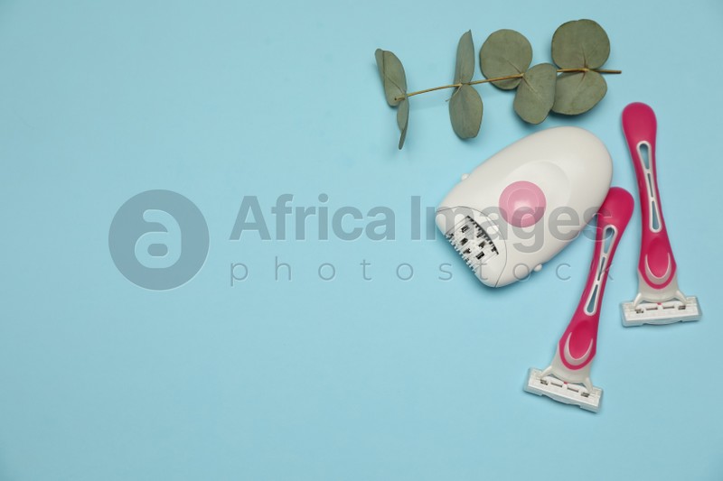 Epilator, razors and eucalyptus on light blue background, flat lay. Space for text