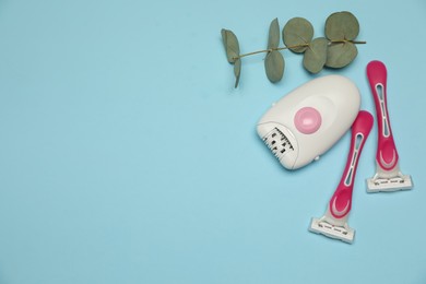 Epilator, razors and eucalyptus on light blue background, flat lay. Space for text