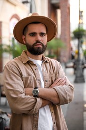Portrait of handsome bearded man in hat on city street