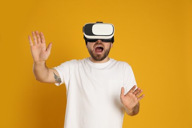 Emotional man using virtual reality headset on yellow background