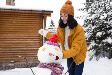 Happy woman making snowman outdoors. Winter vacation