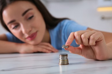 Young woman stacking coins at table, focus on hand. Money savings