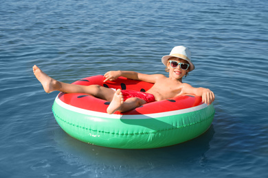 Cute little child with inflatable ring in sea on sunny day. Beach holiday