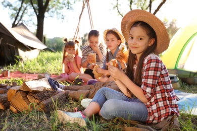 Photo of Little girl eating sandwich outdoors. Summer camp